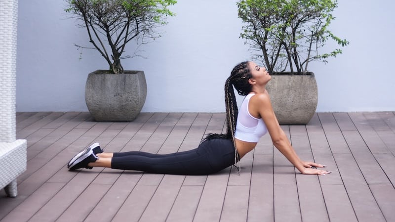 Woman stretching in a white top and black yoga pants