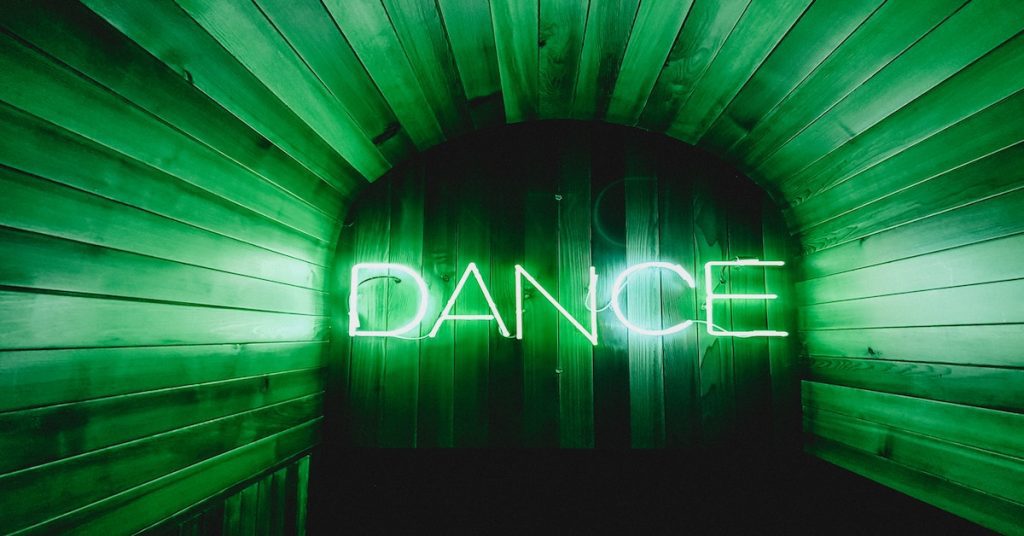 The word "Dance" in neon green lights