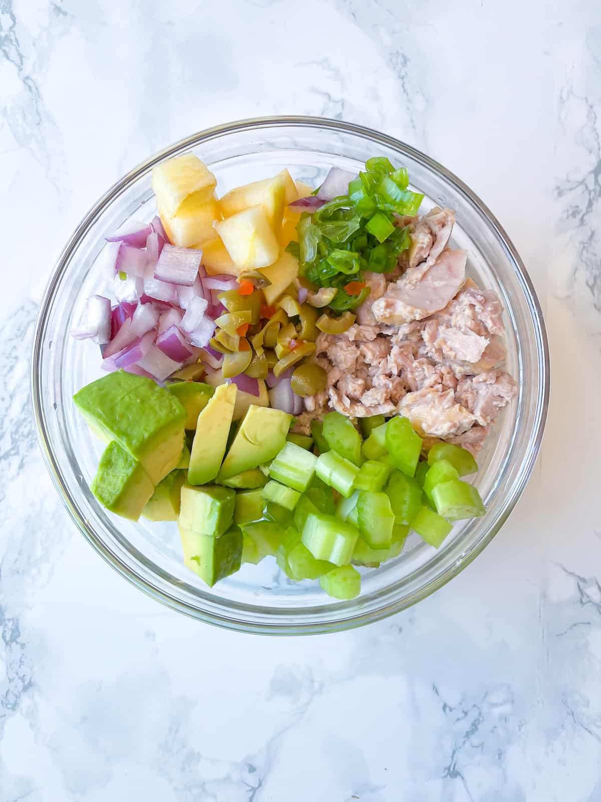 Dairy Free Tuna Salad step two with apple, avocado, celery, red onions, green onions, olives, apples, and fresh tuna in a medium bowl