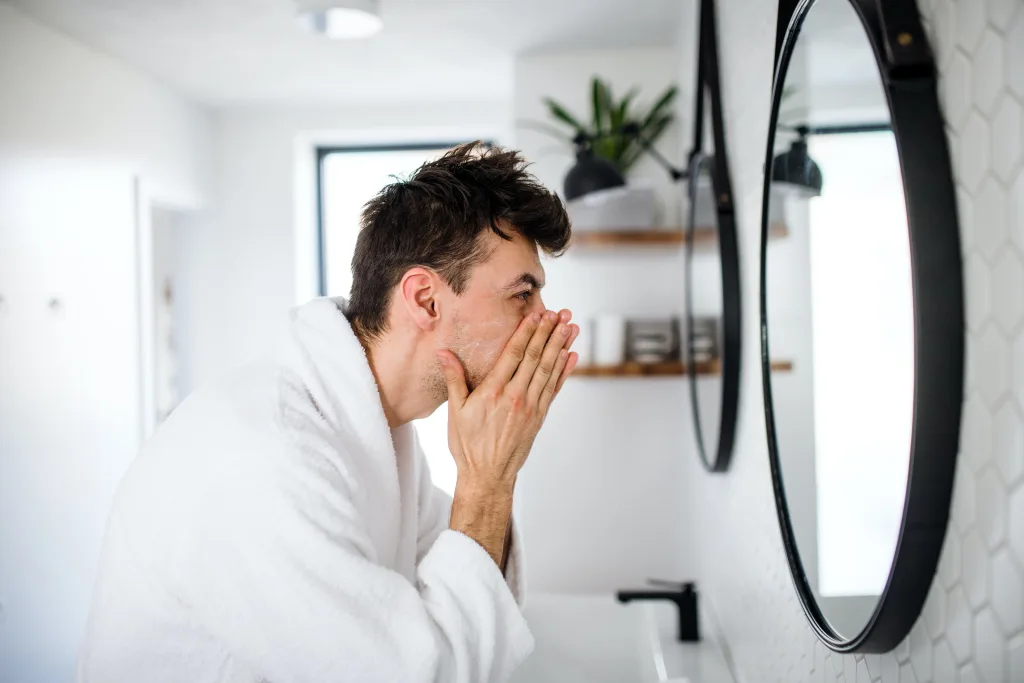 a man washing his face as part of his morning routine checklist