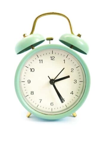 A turquiose alarm clock on a white background
