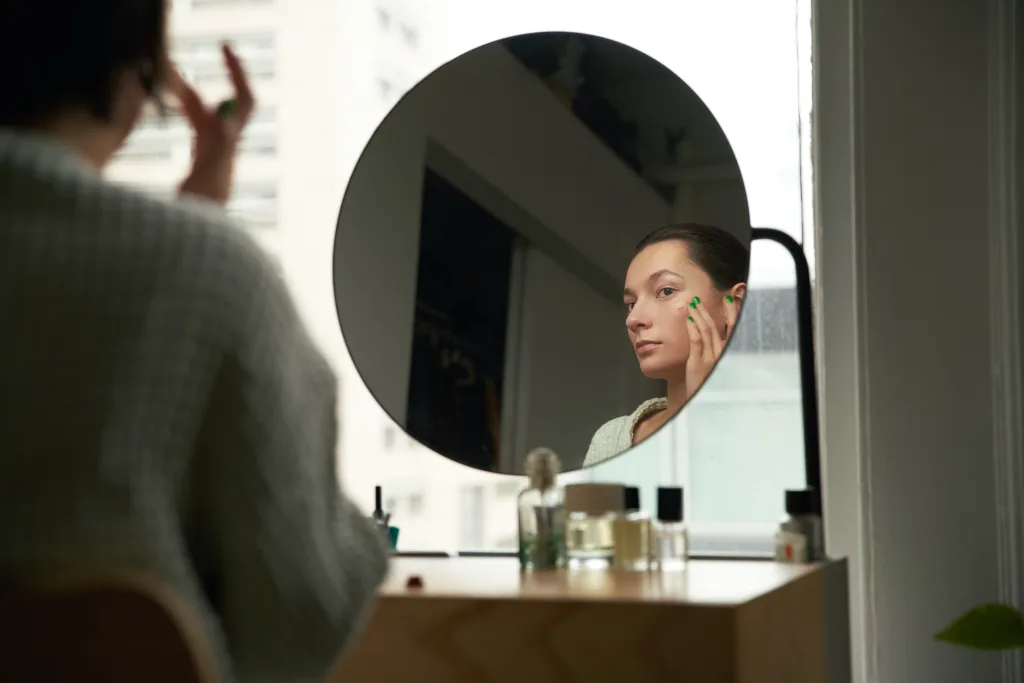 a woman looking in the mirror and getting ready