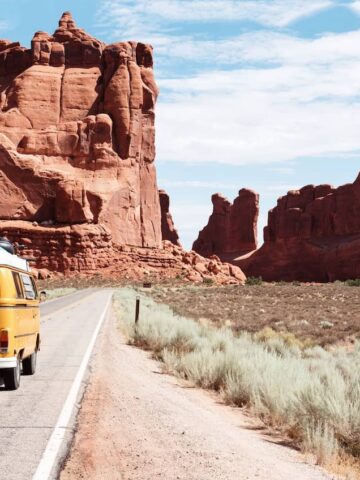 A yellow van driving in the terracotta colored rocks