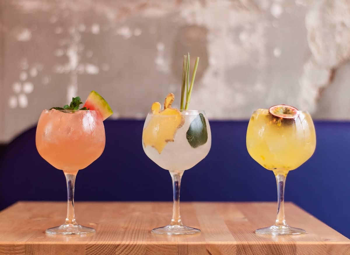 3 cocktails or mocktails on a bar in pretty glasses 