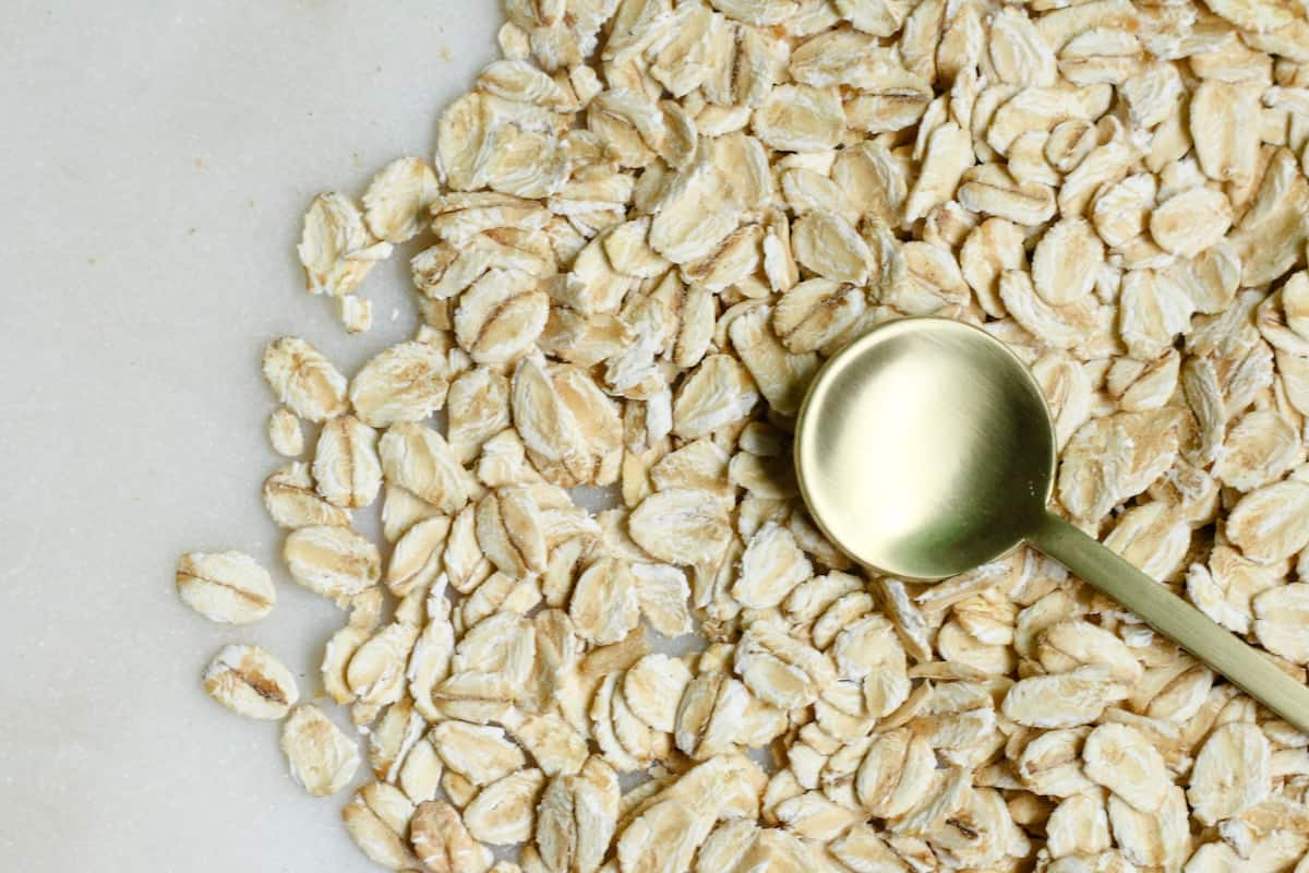 A close up of oats with a gold spoon. Oatmeal is rich in fiber and good for balancing hormones at breakfast