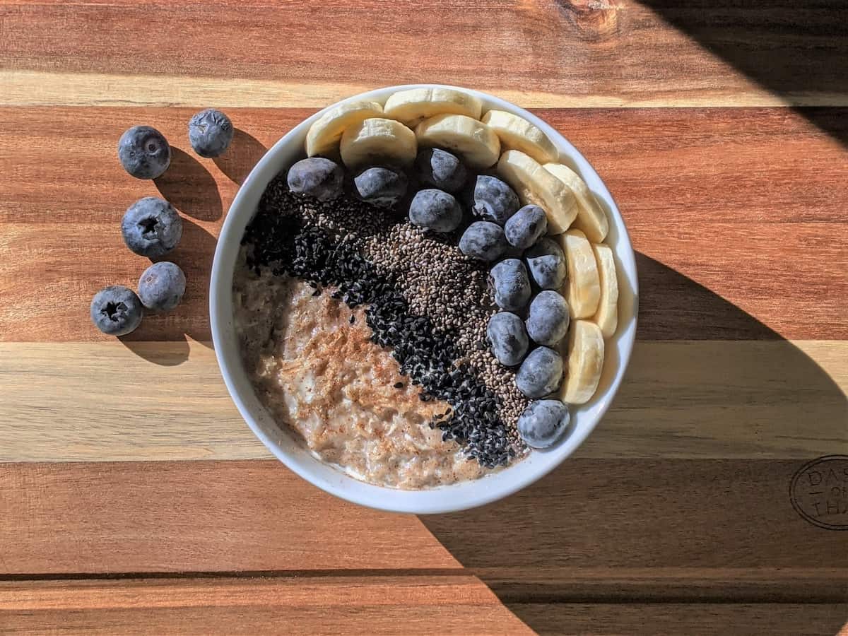 a bowl of oatmeal with blueberries, banana, and seeds which is a hormone balancing breakfast