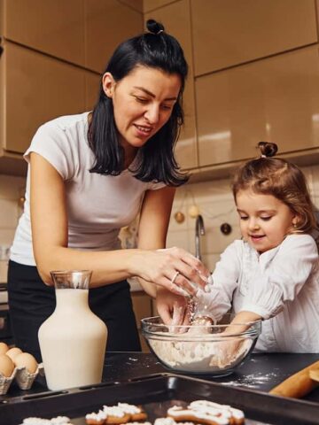 A woman in the kitchen cooking with a child