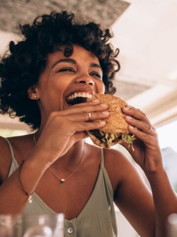 A woman eating a burger and smiling