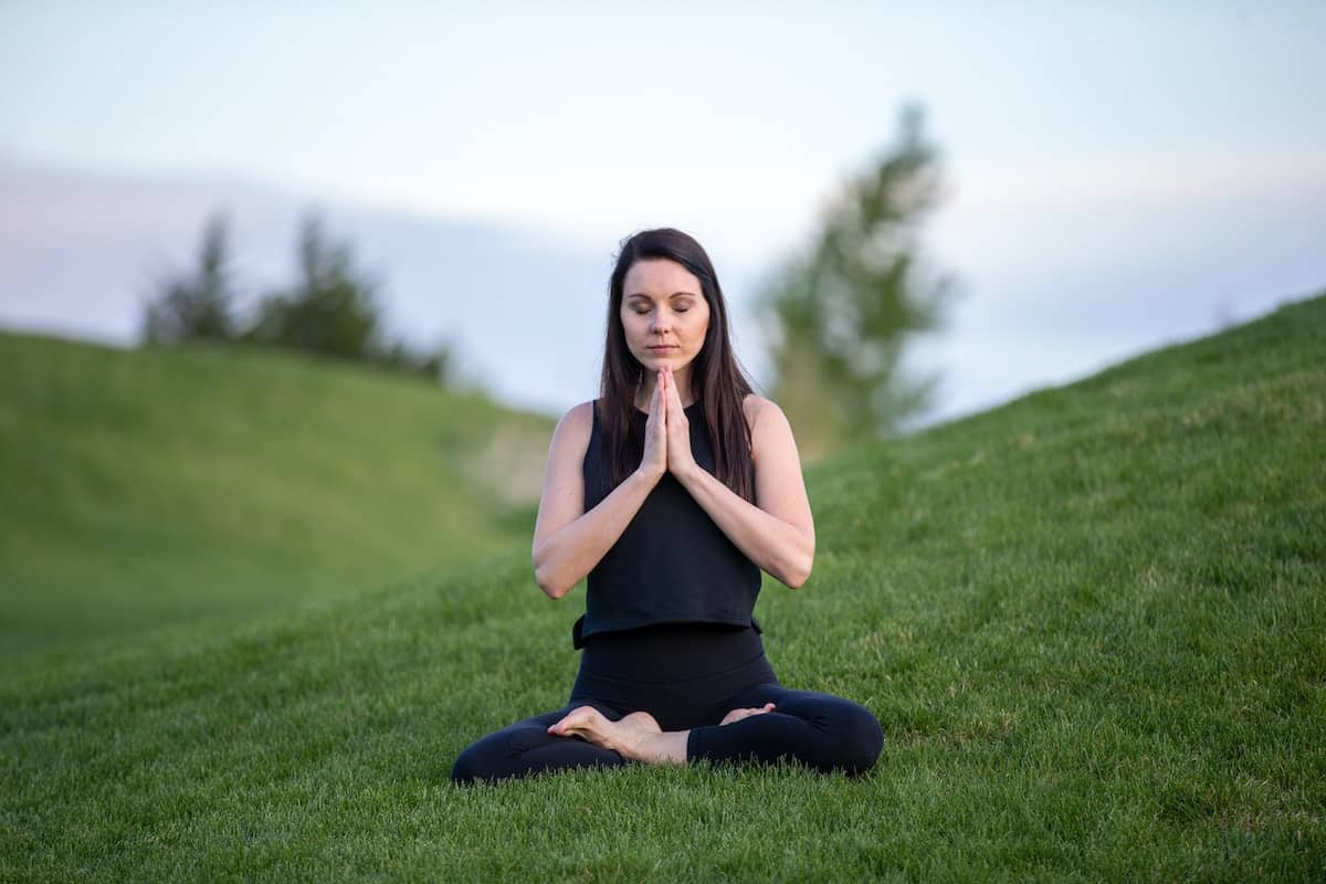 A woman meditating on green grass
