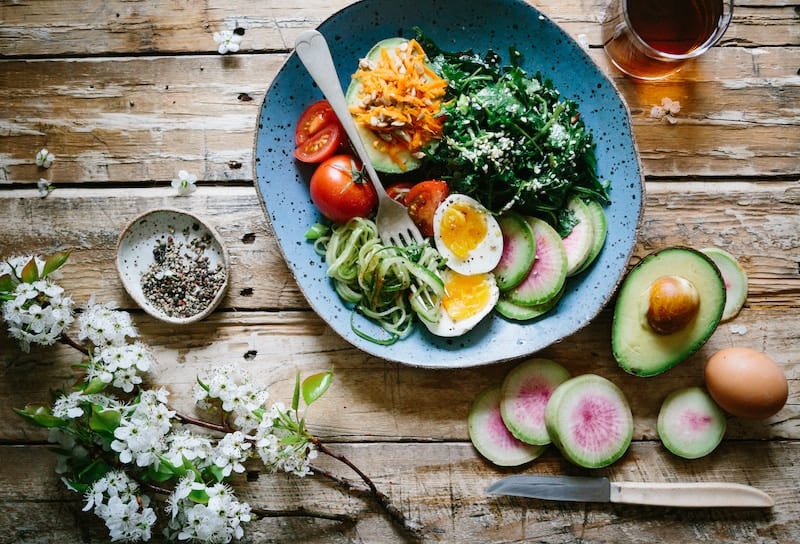 The top 10 foods for mental health and functional nutrition includes things like the foods pictured here. A bowl with dark leafy greens, egg, and avocado