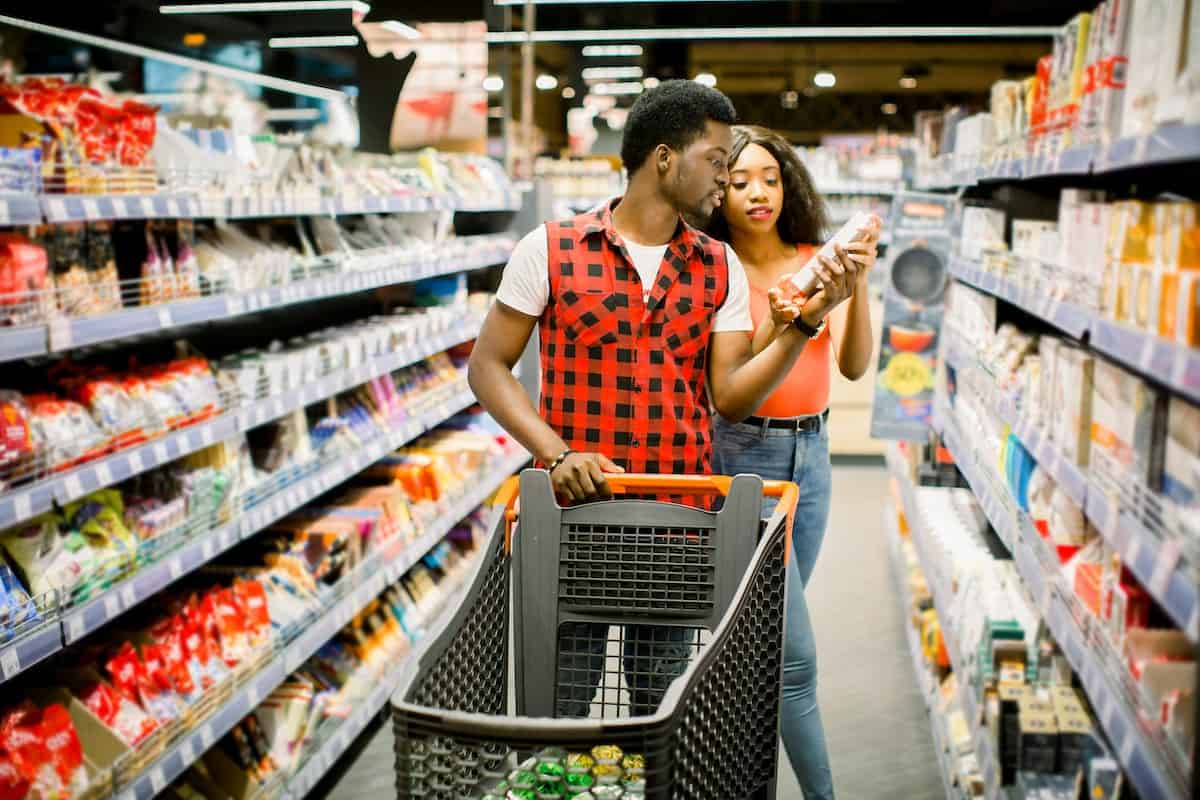 a couple who is grocery shopping and looking at labels on food