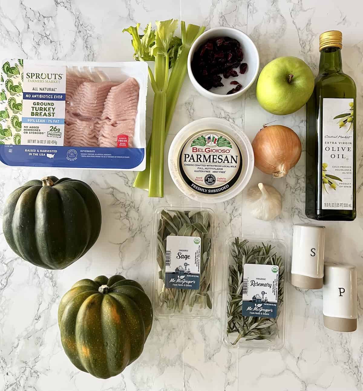 The ingredients to make ground turkey stuffed acorn squash on a white marble table