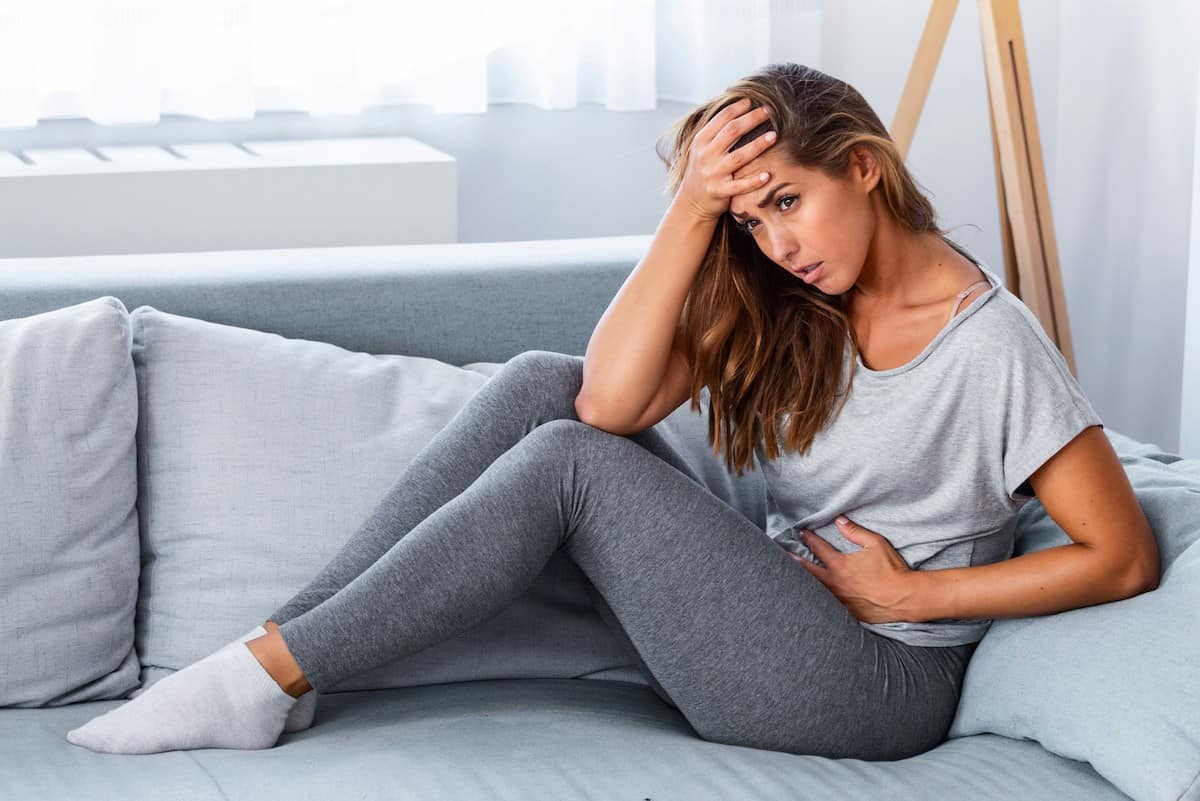 a woman with cramps in a gray outfit