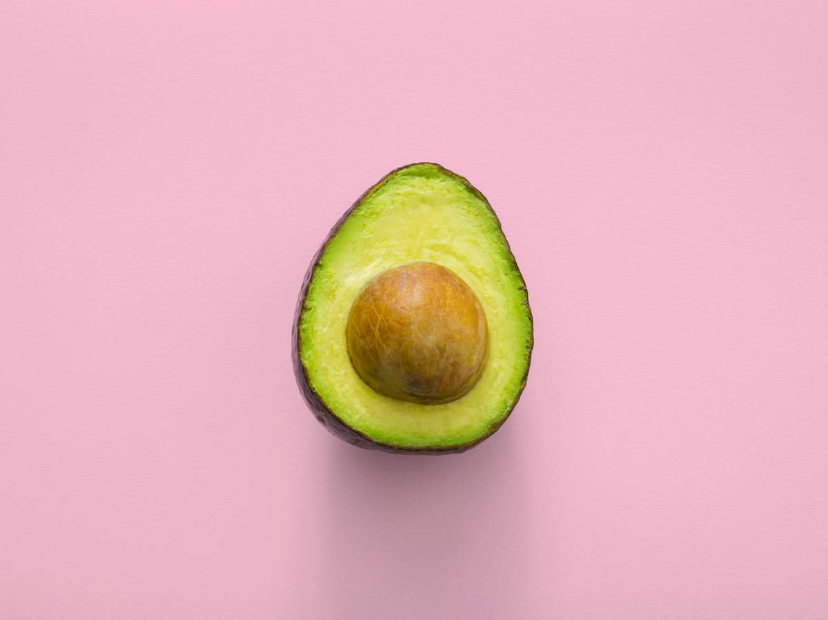 an avocado on a pink backdrop