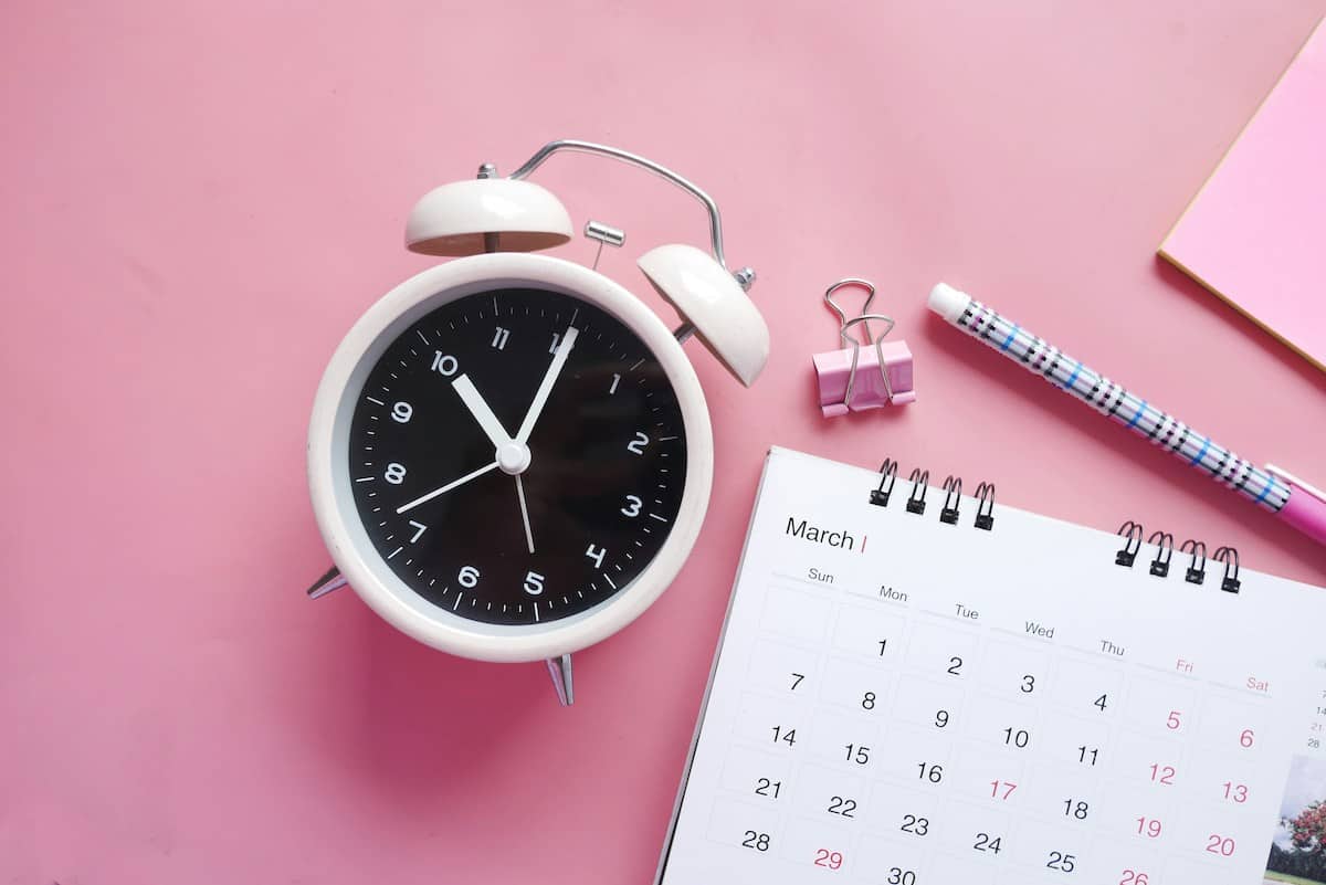a pink background with a clock and calendar