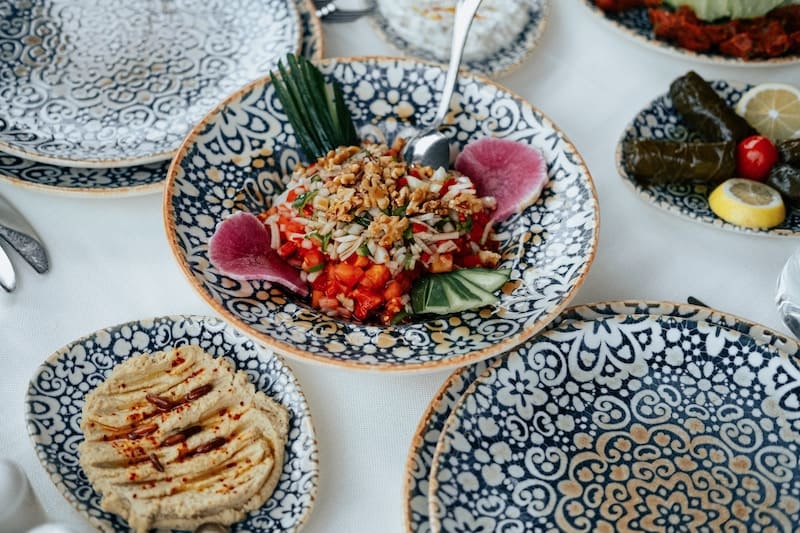 A hormone balancing foods include many that are in the mediterranean diet like those pictured here. A hummus and some vegetables on blue plates.