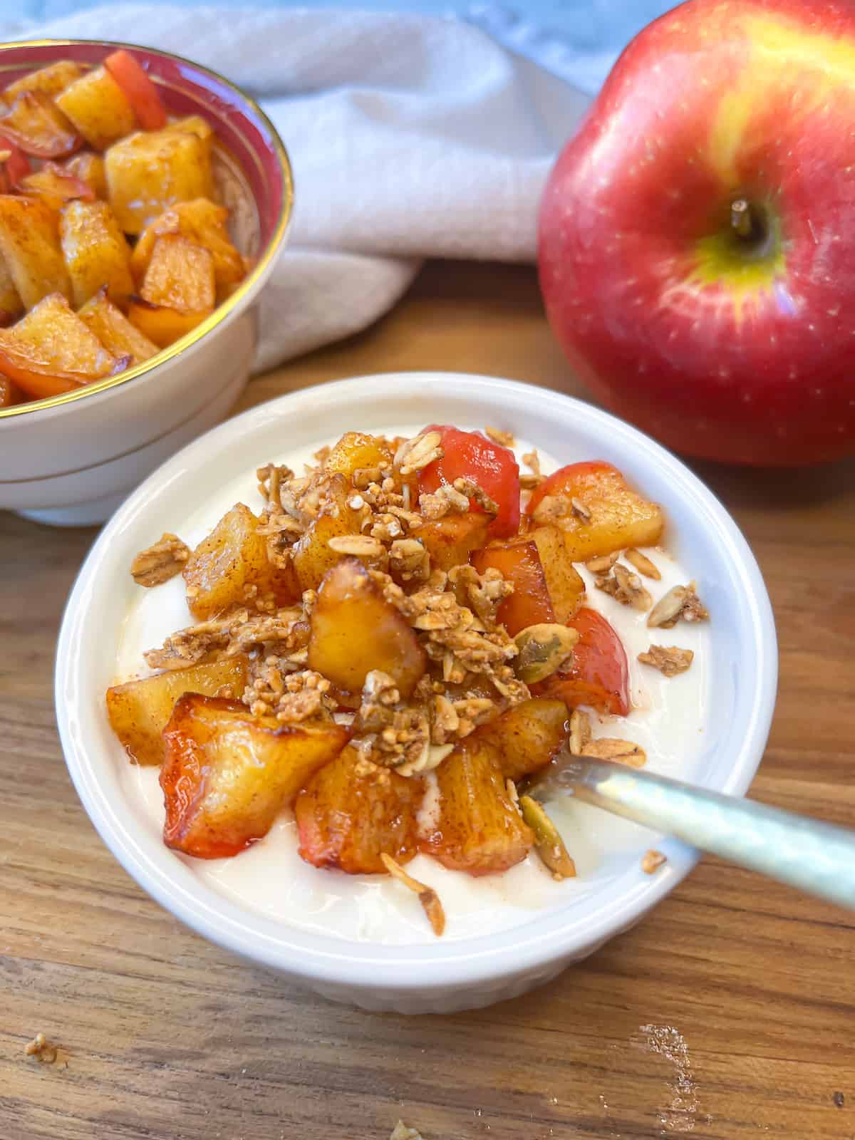 air fryer apples with greek yogurt and granola and an apple in the background