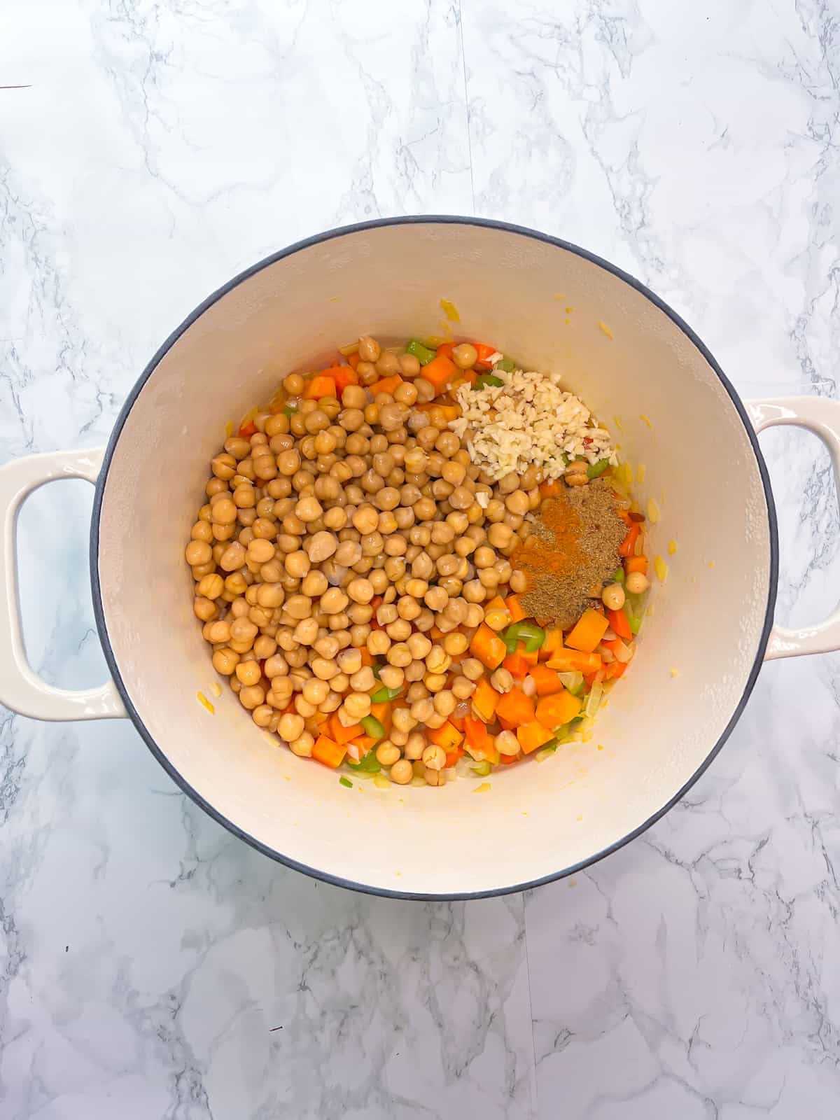 chickpeas, garlic, spices added to the dutch oven with carrots celery onion and sweet potaoes