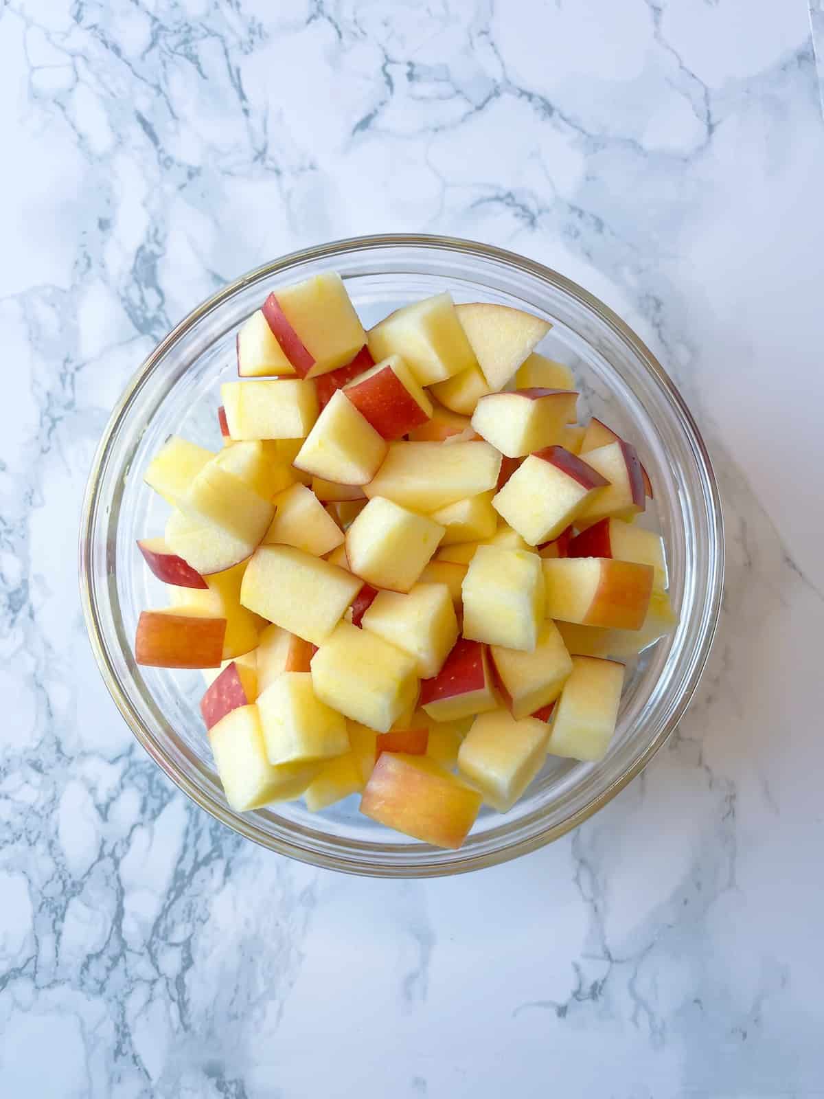 diced apple in a glass bowl on a marble table