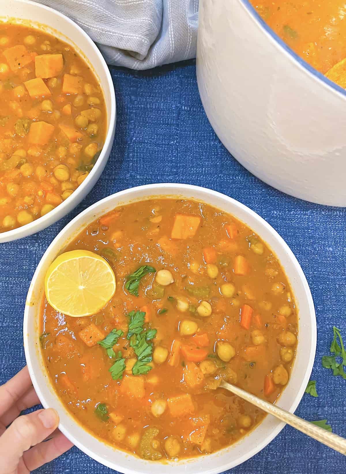 mediterranean chickpea soup in a bowl with a hand holding it