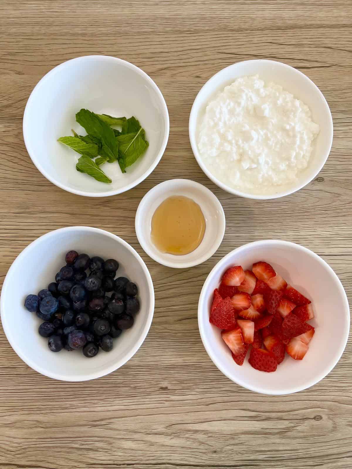 Cottage cheese with fruit ingredients on a wooden background in white bowls. 