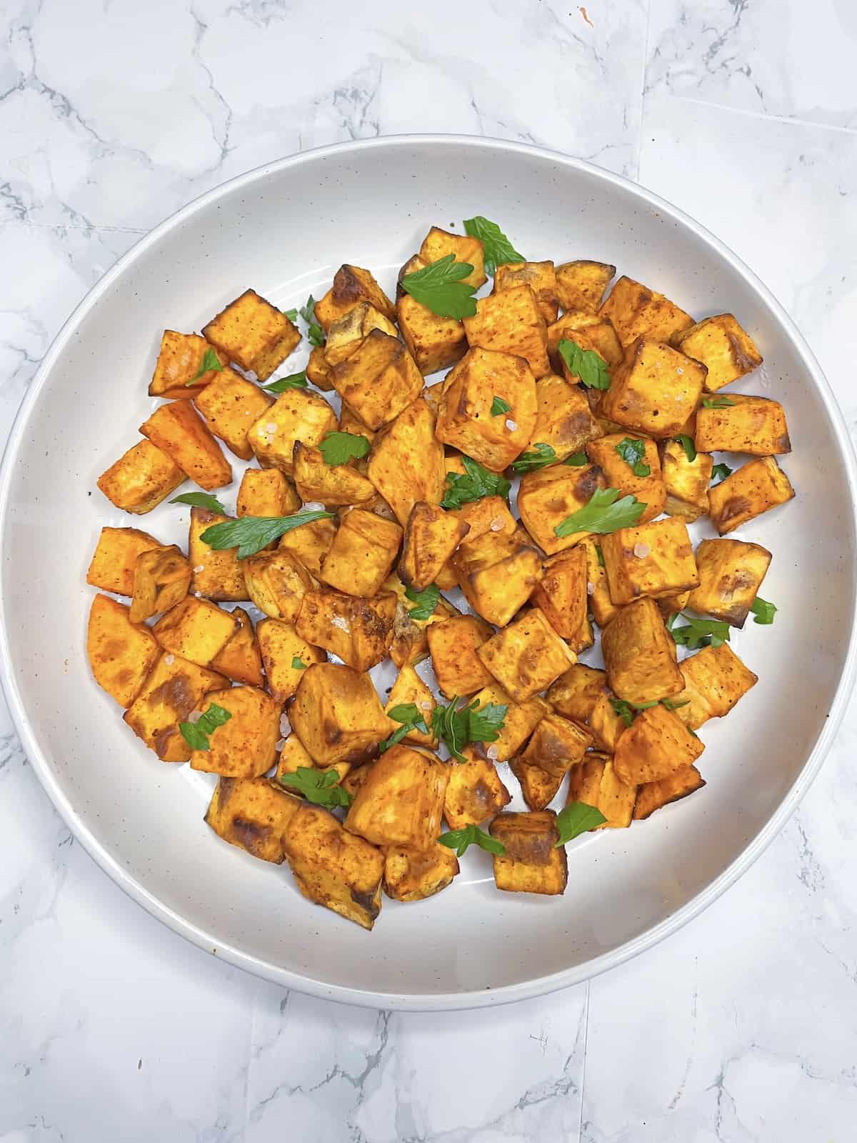 air fryer diced sweet potato in a white bowl on a marble table