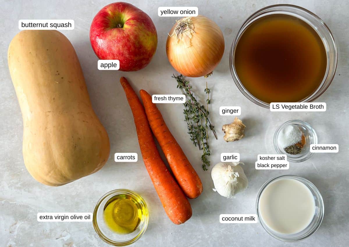 Ingredients for butternut squash soup on a grayish white background in separate containers.