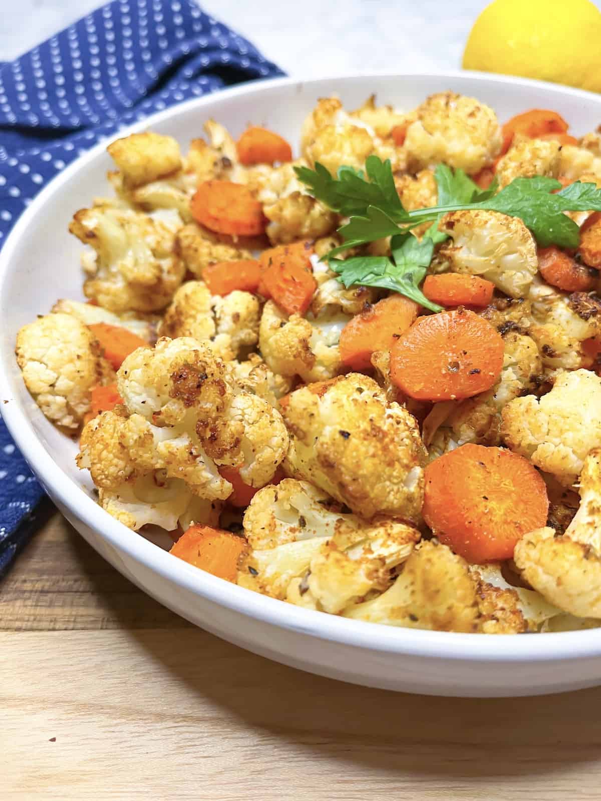 roasted cauliflower and carrots with lemon behind it