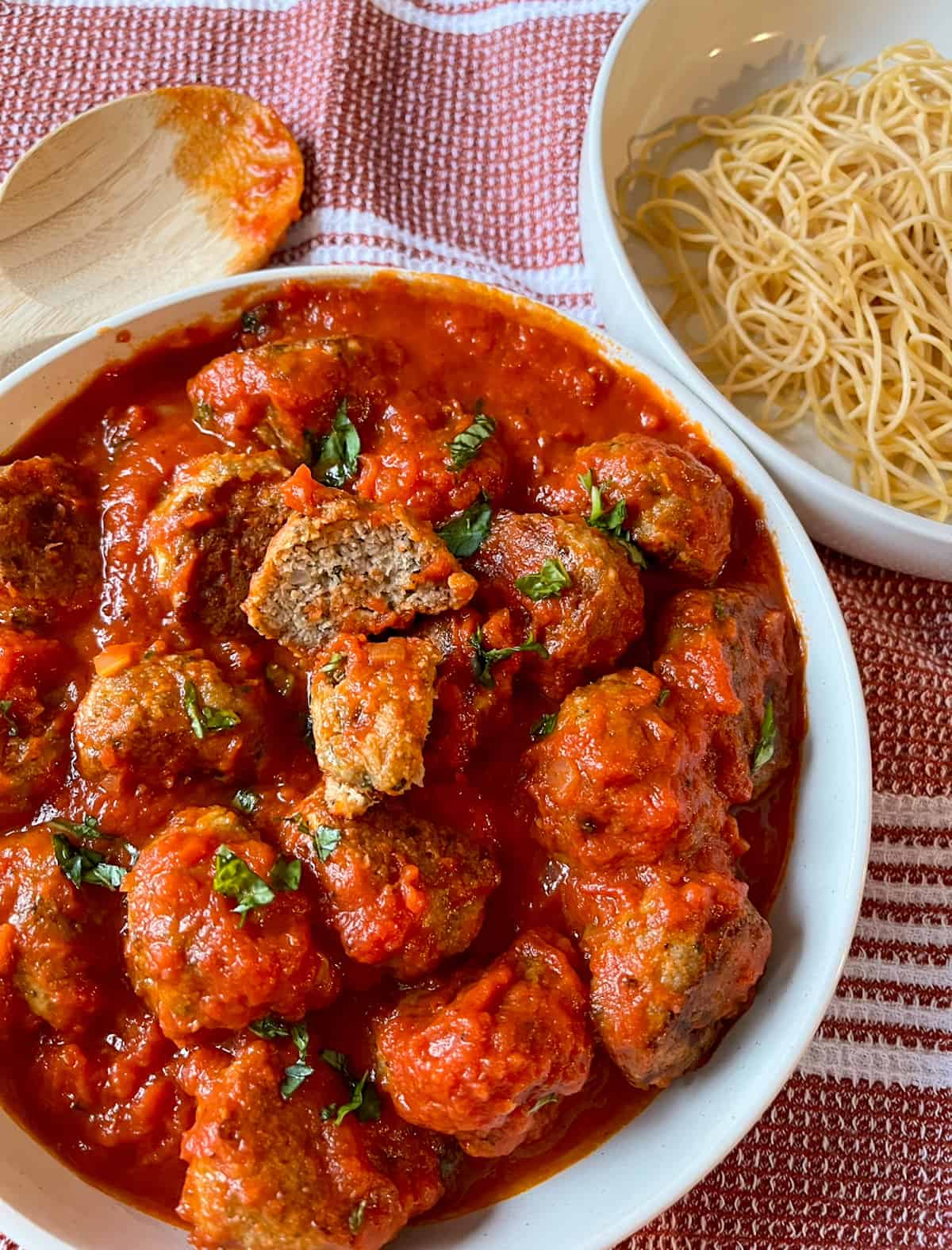 Gluten-free turkey meatballs with marinara sauce in a bowl with gluten-free pasta in another bowl
