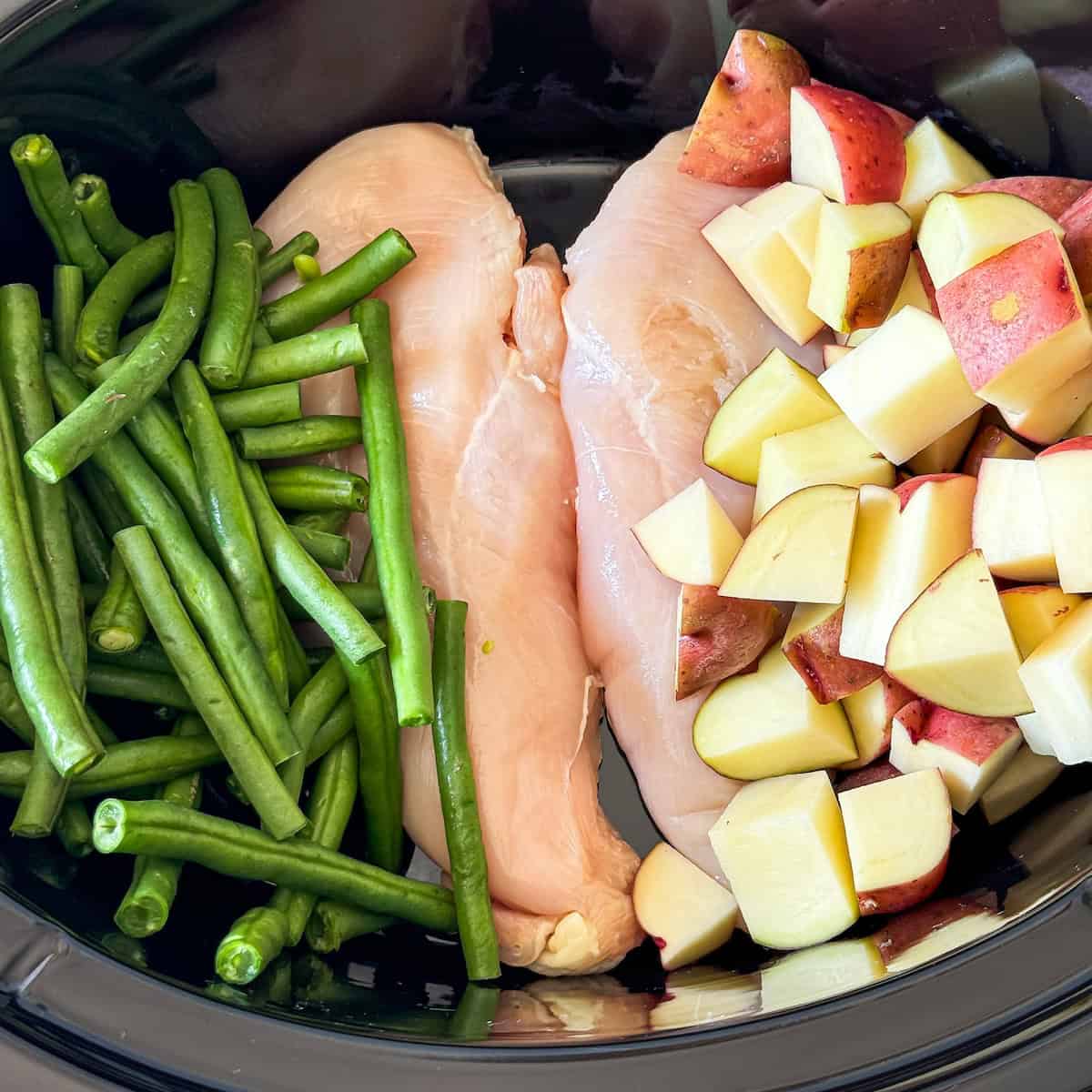 chicken, green beans, and potatoes in a slow cooker.