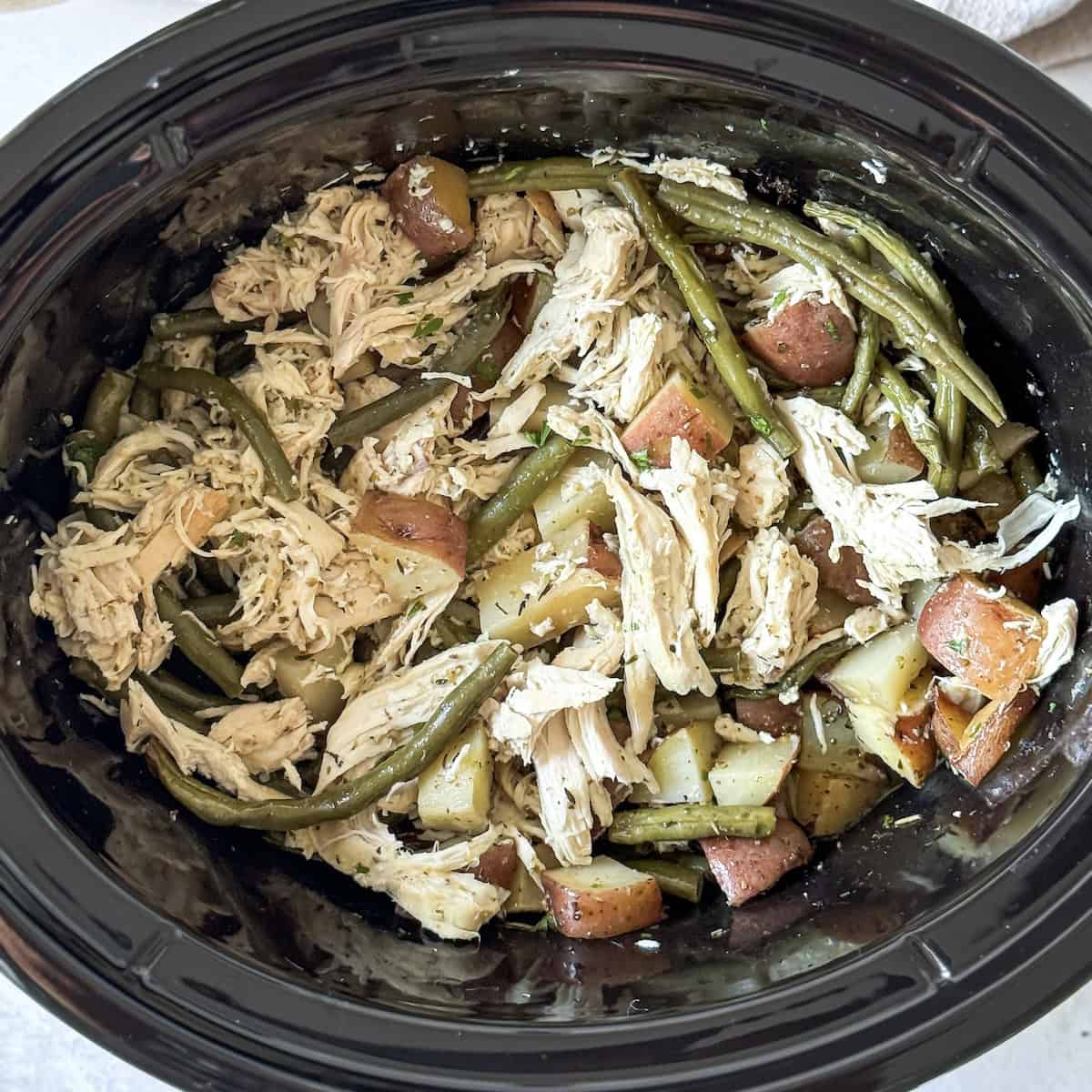 shredded slow cooker chicken, green beans and potatoes from an overhead view.