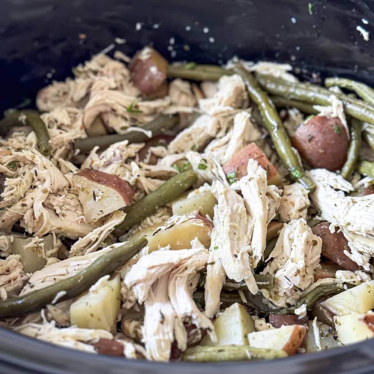 a close up of shredded chicken, green beans, and potatoes.