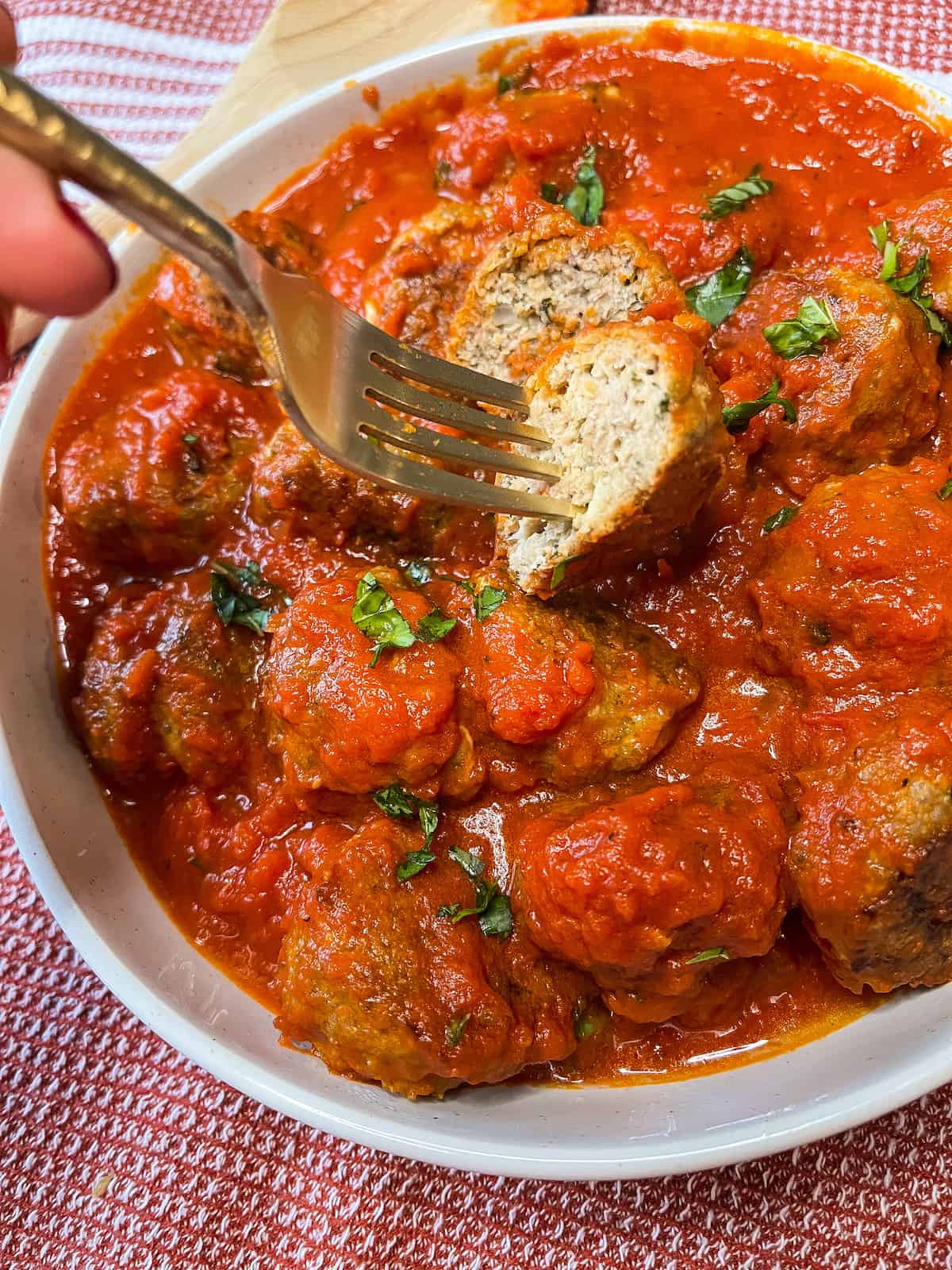 gluten-free turkey meatballs in tomato sauce with a fork and real human hand