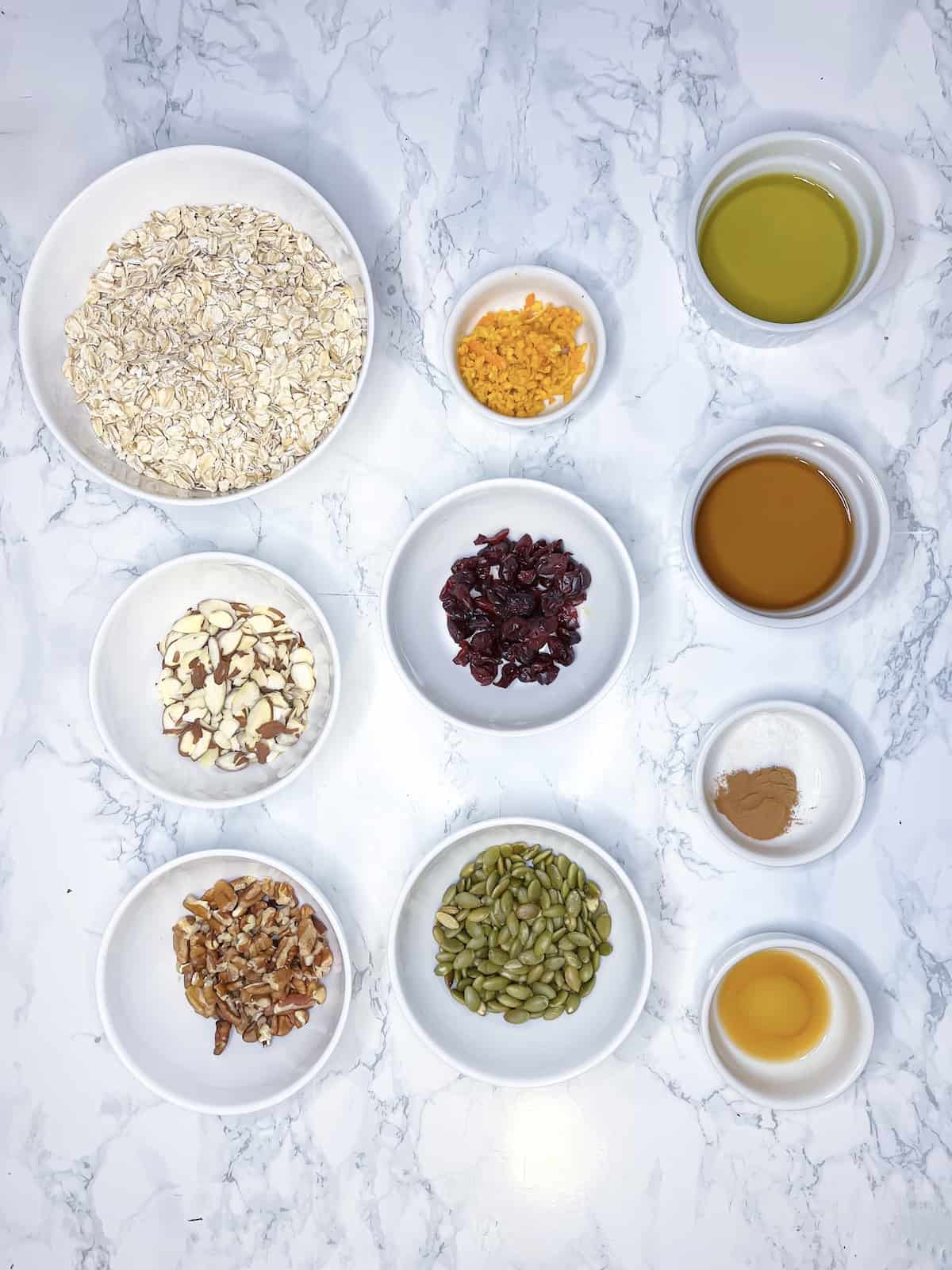 ingredients for homemade orange cranberry granola on a marble table