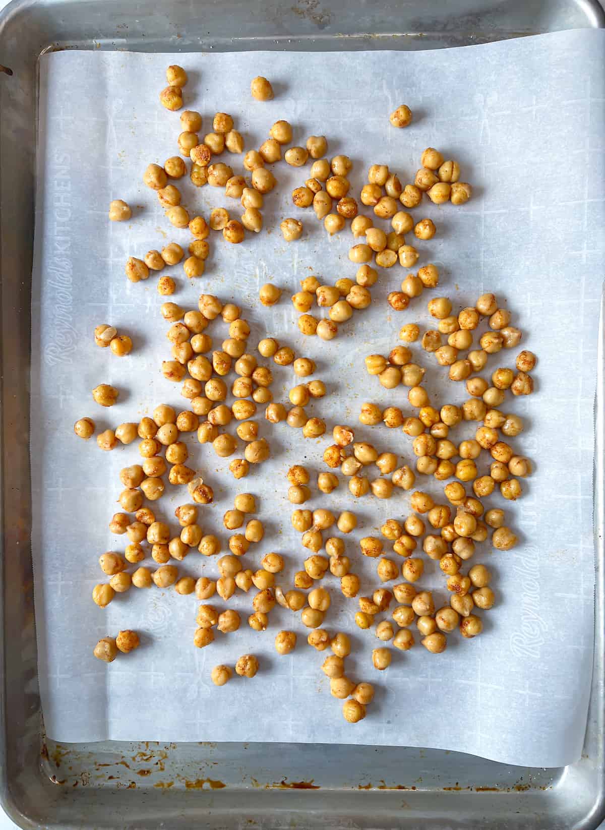 Chickpeas in a single layer on a large baking sheet lined with parchment paper