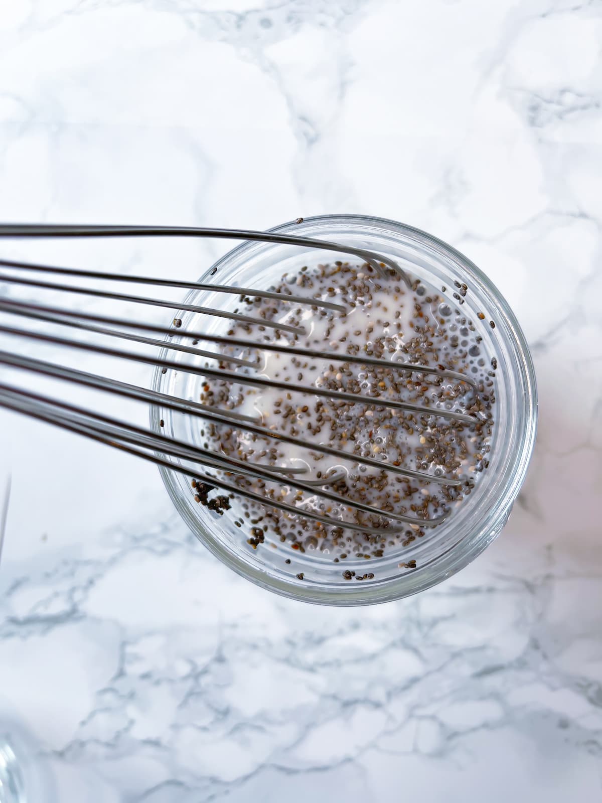 a hand whisking together plant based milk and chia seeds