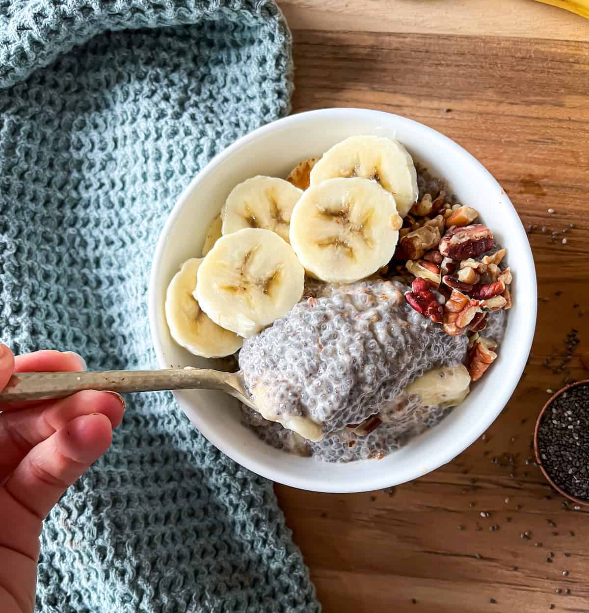 banana chia seed pudding with a hand taking a bite