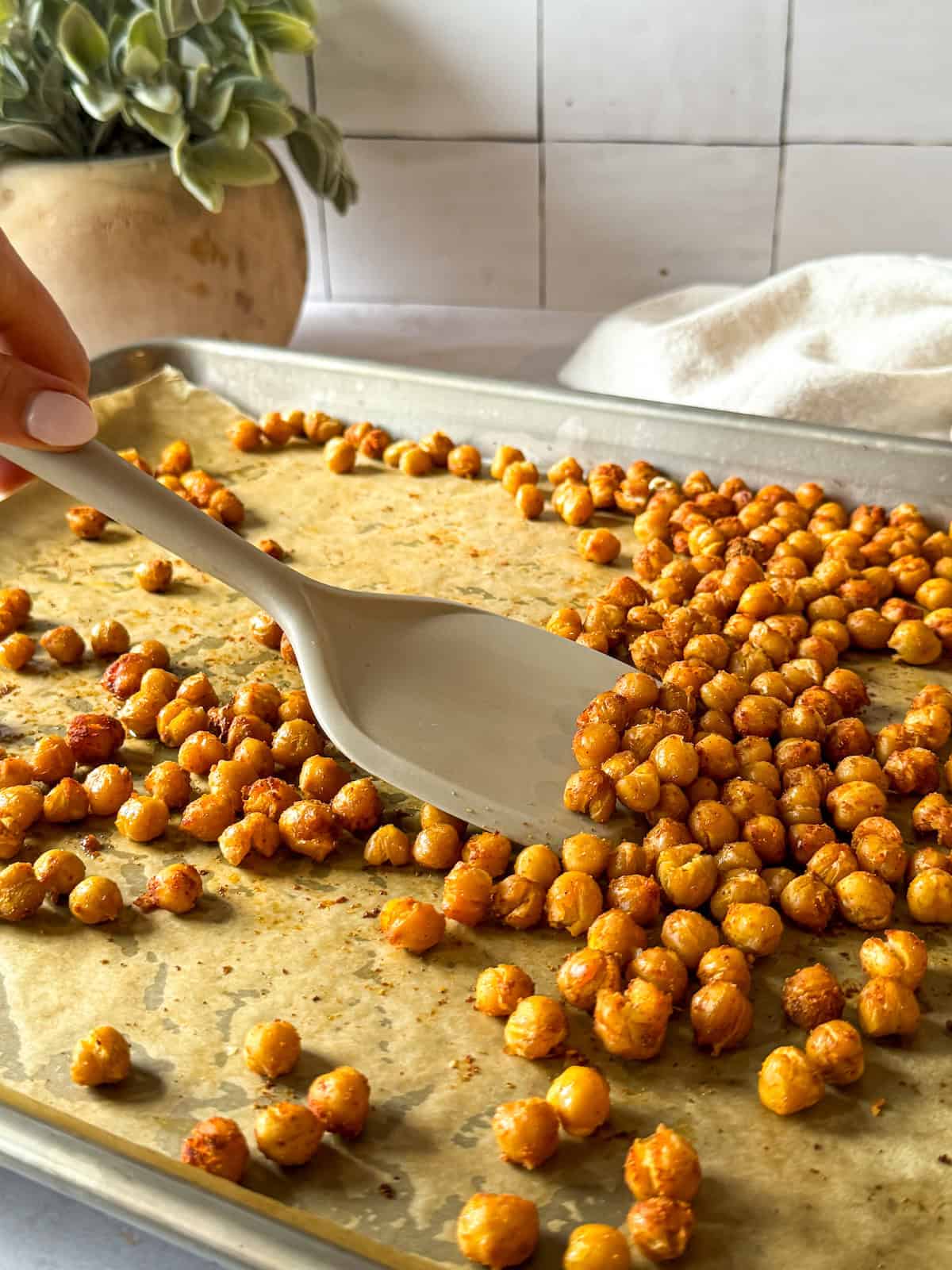a hand mixing mediterranean roastee chickpeas.