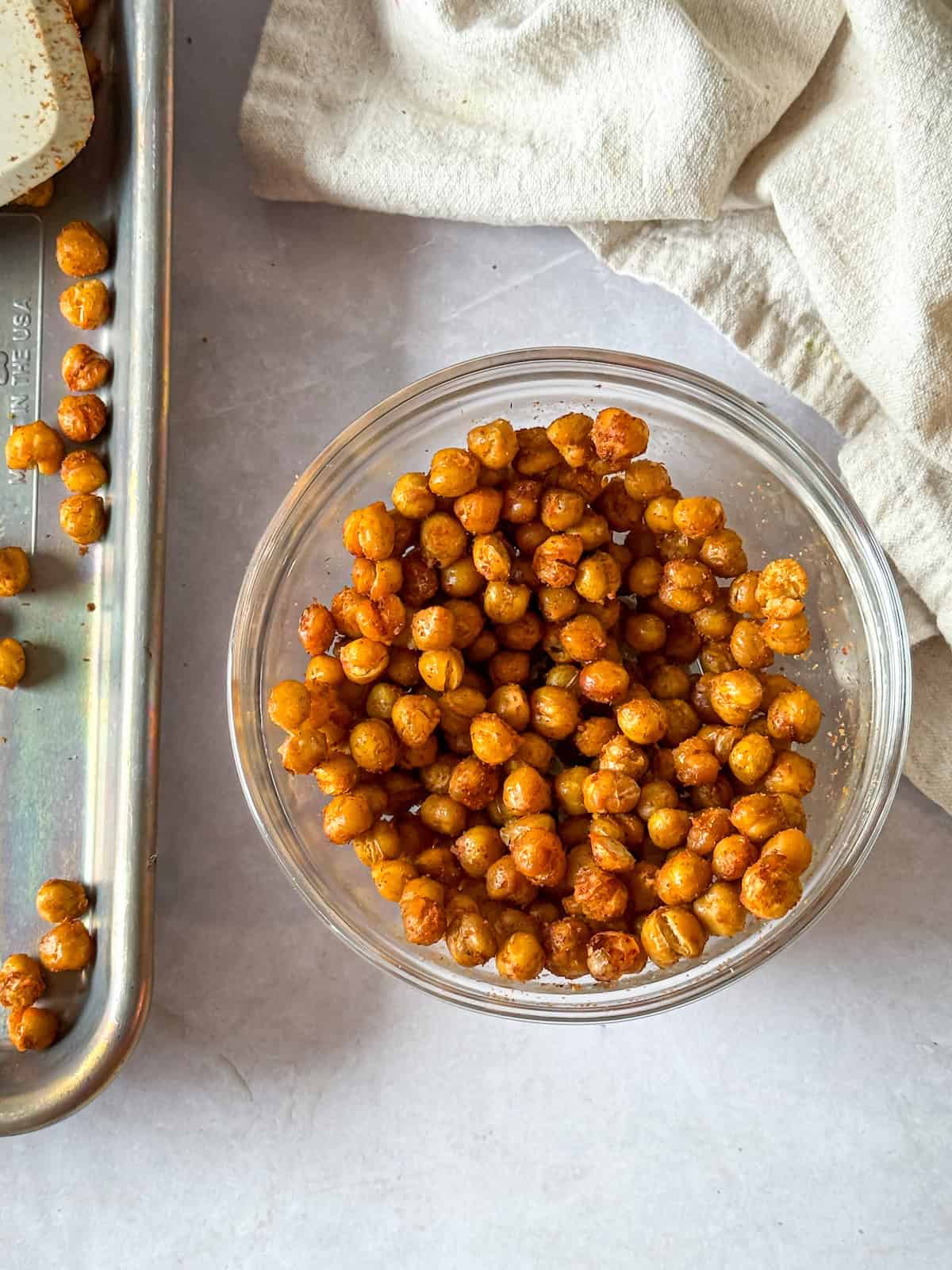 Mediterranean roasted chickpeas on a baking sheet and in a glass bowl.