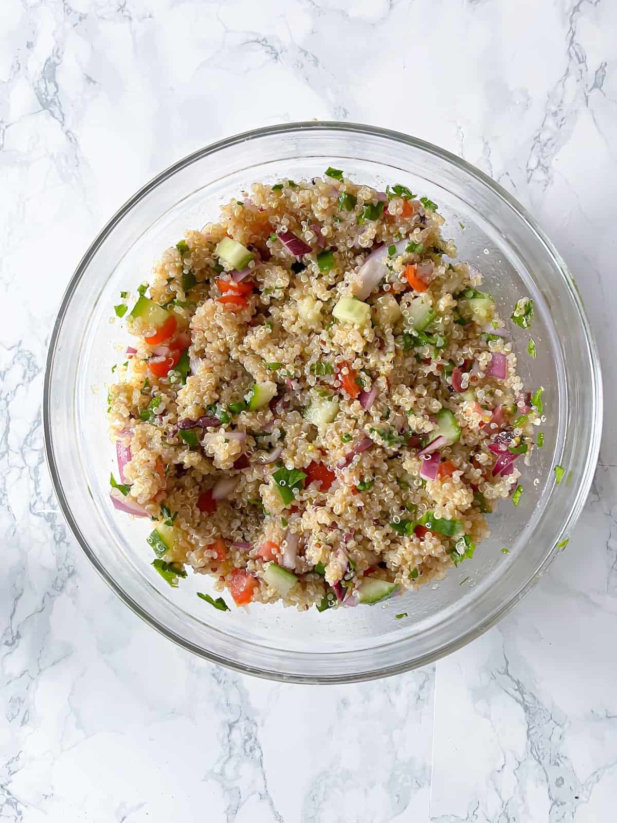 quinoa salad in a glass bowl with fresh veggies and a lemon olive oil dressing