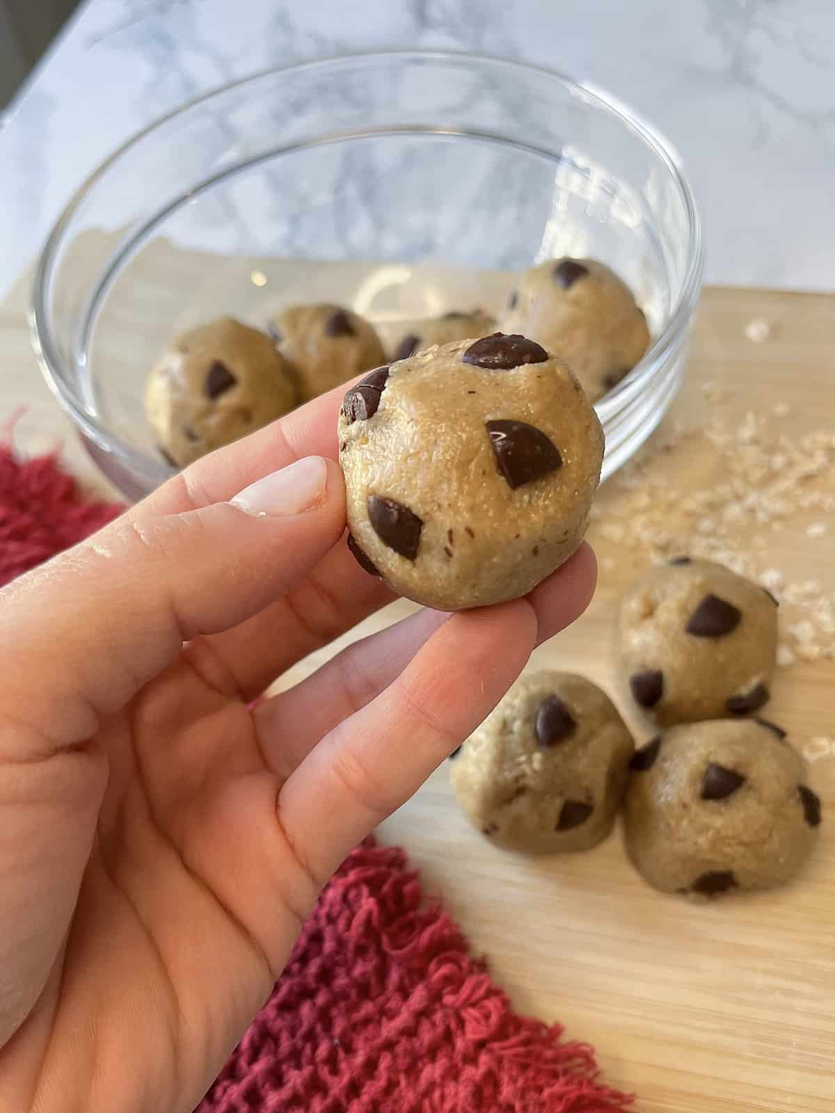 a hand holding a protein cookie dough bite with more in the background