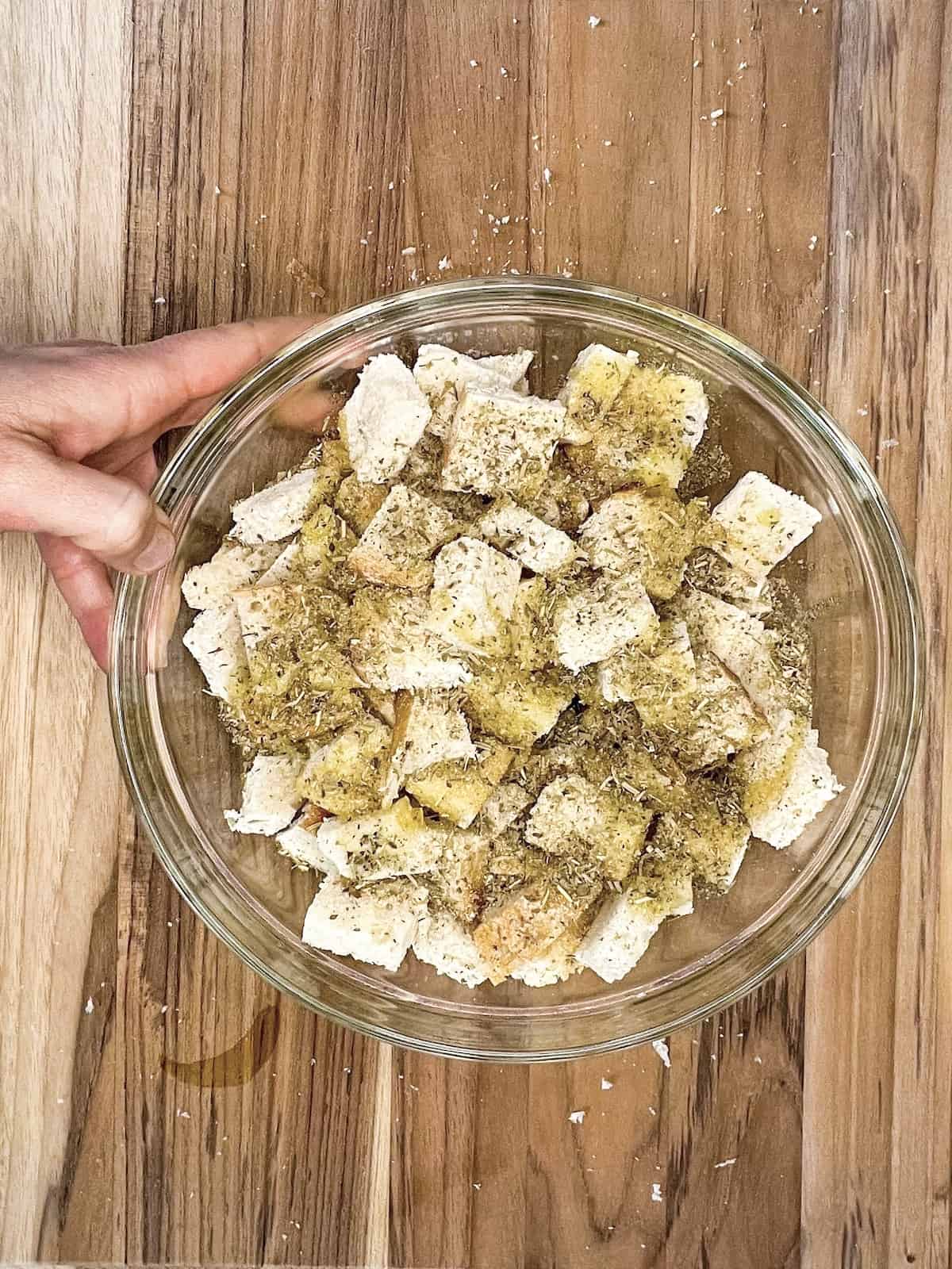 a large bowl of bread cubes with spice blend and oil on top