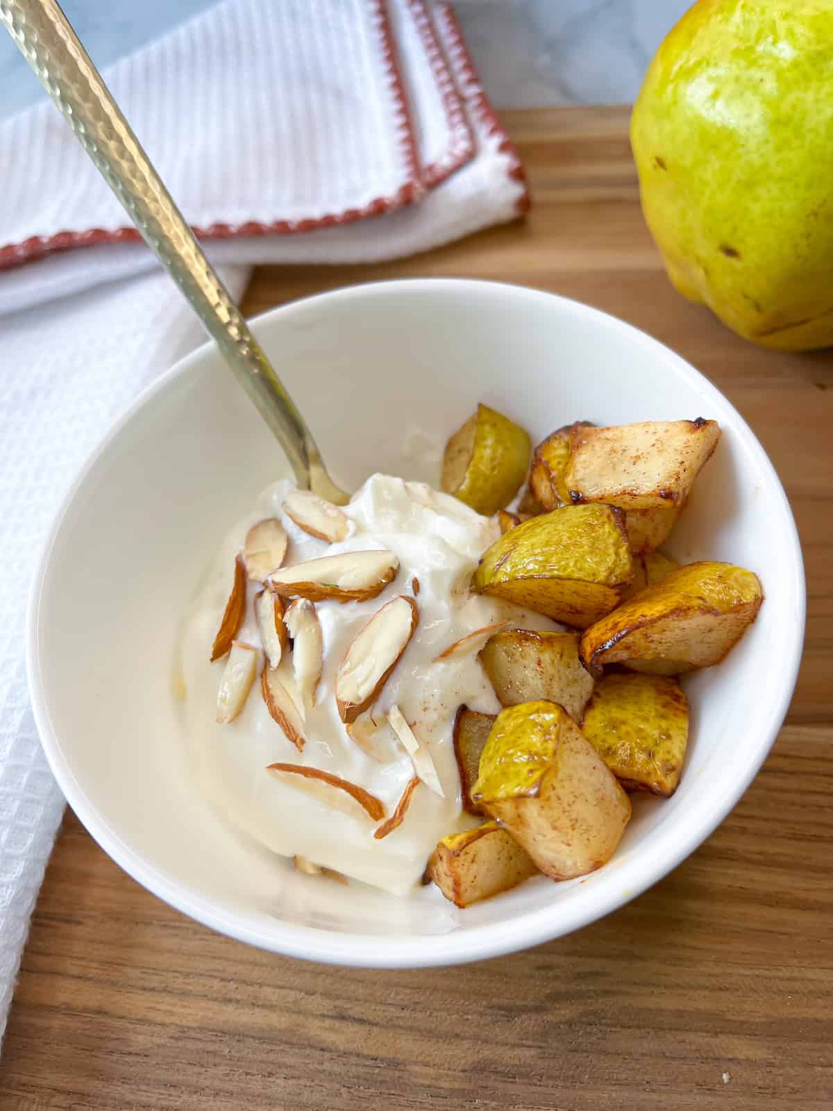 air fryer pears with greek yogurt and a bartlett pear in the background