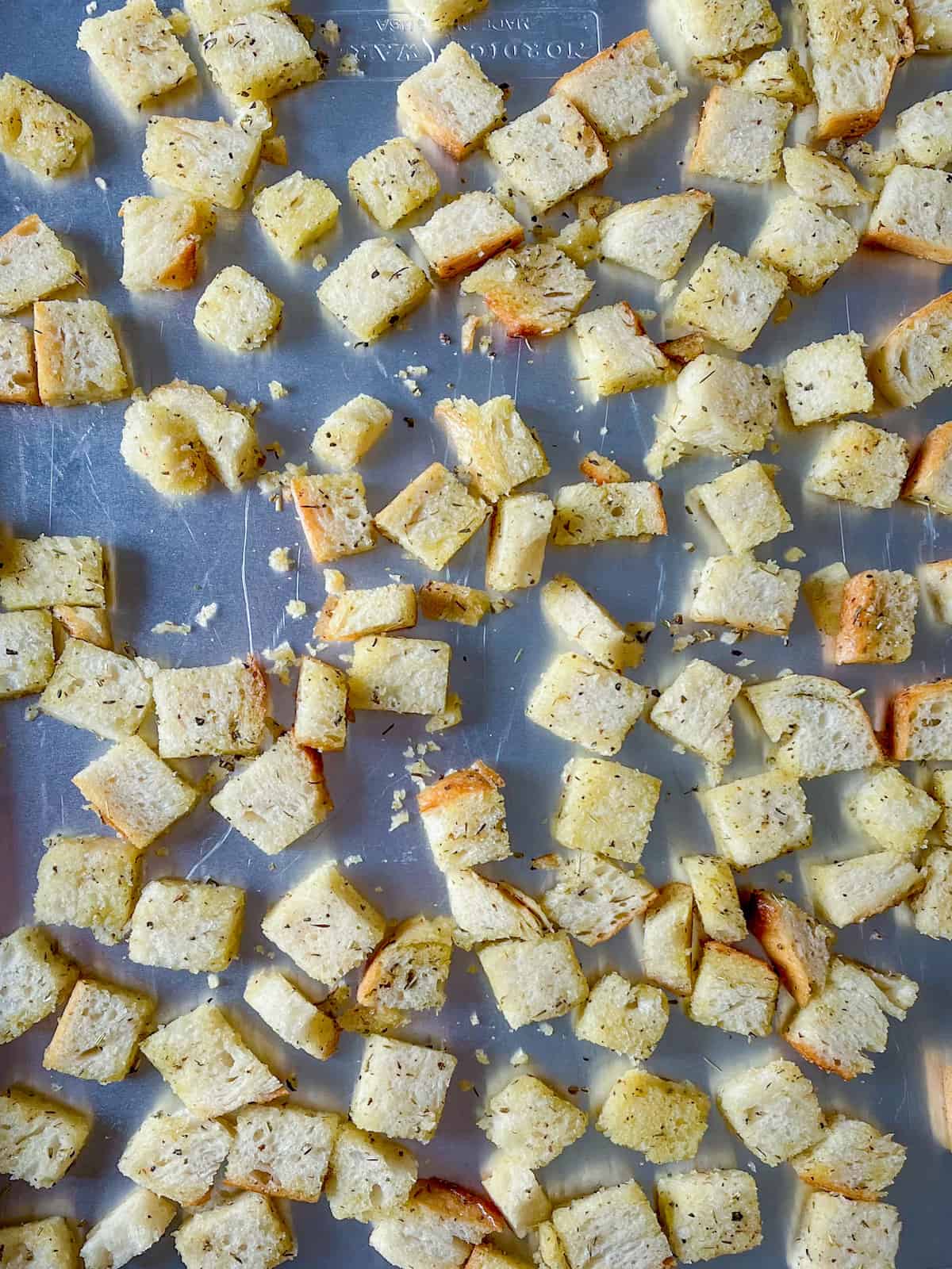 bread cubes coated in olive oil and spice blend on a baking sheet