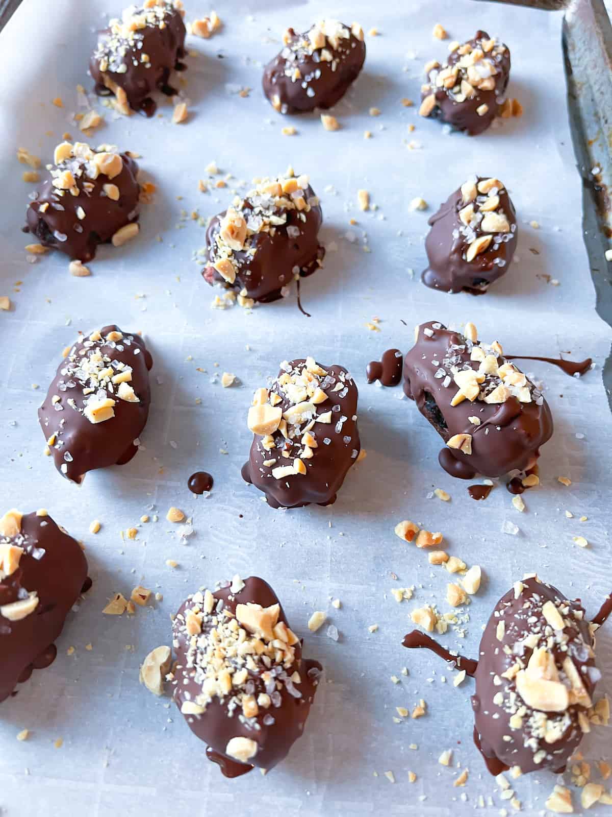 date snickers on a parchment-paper lined baking sheet covered in chocolate