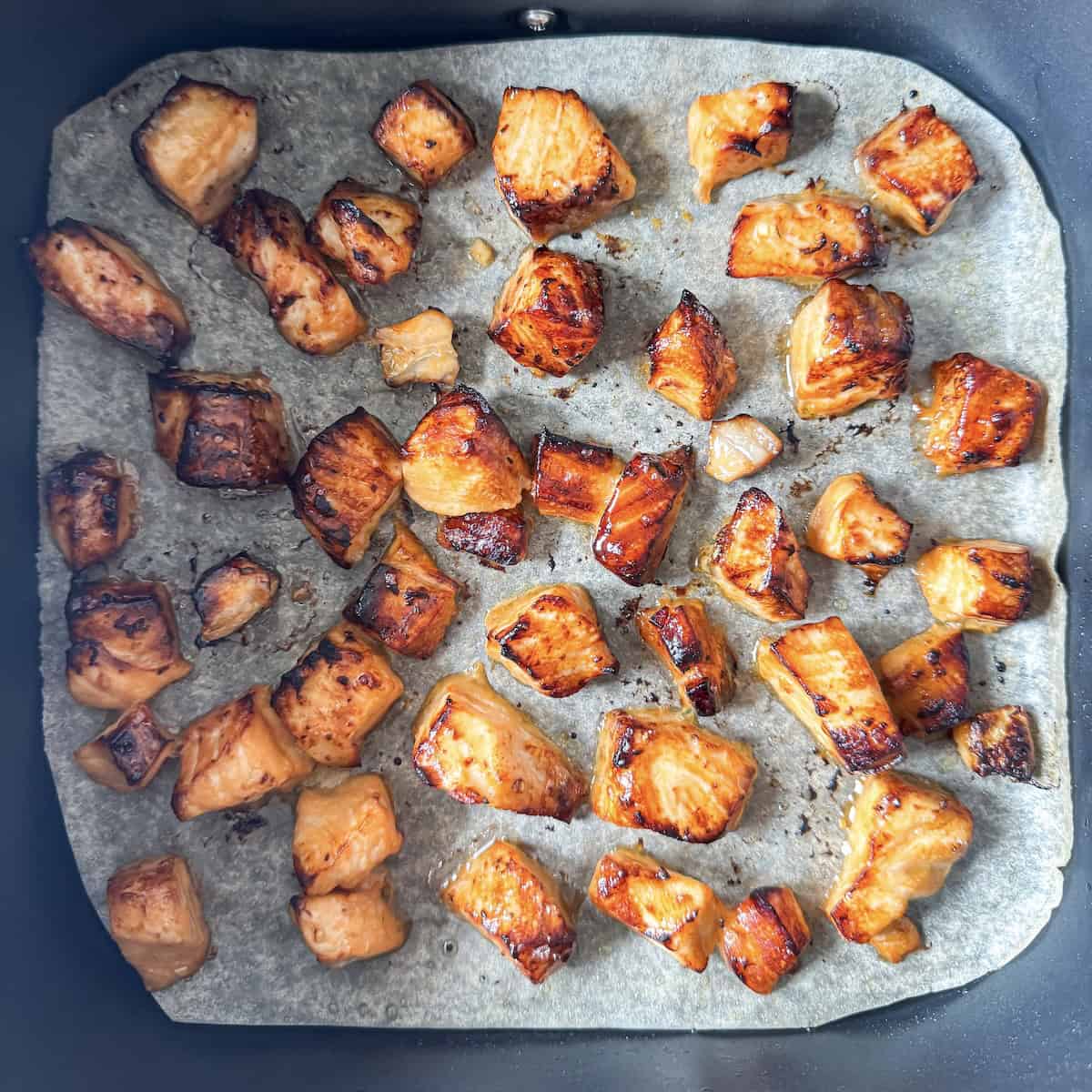 overhead view of salmon bites in an air fryer.