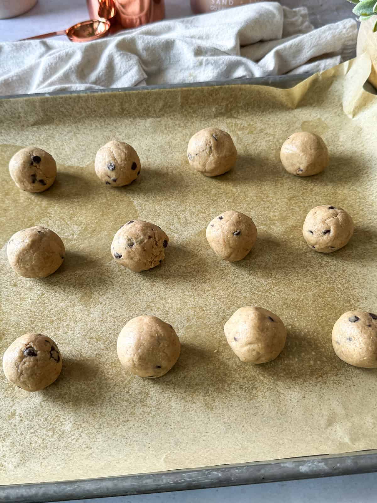 Protein cookie dough balls on a baking sheet lined with parchment paper. 