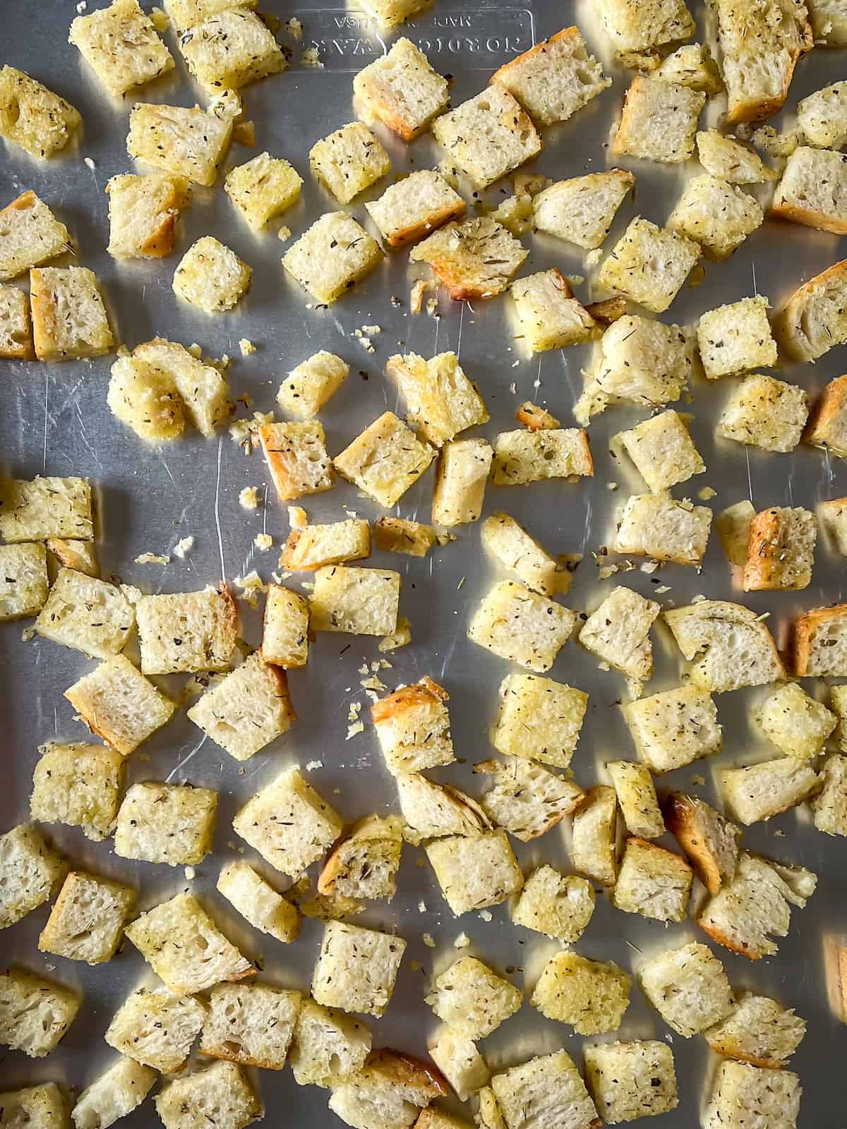 sourdough bread cubes coated in olive oil and spice blend on a baking sheet