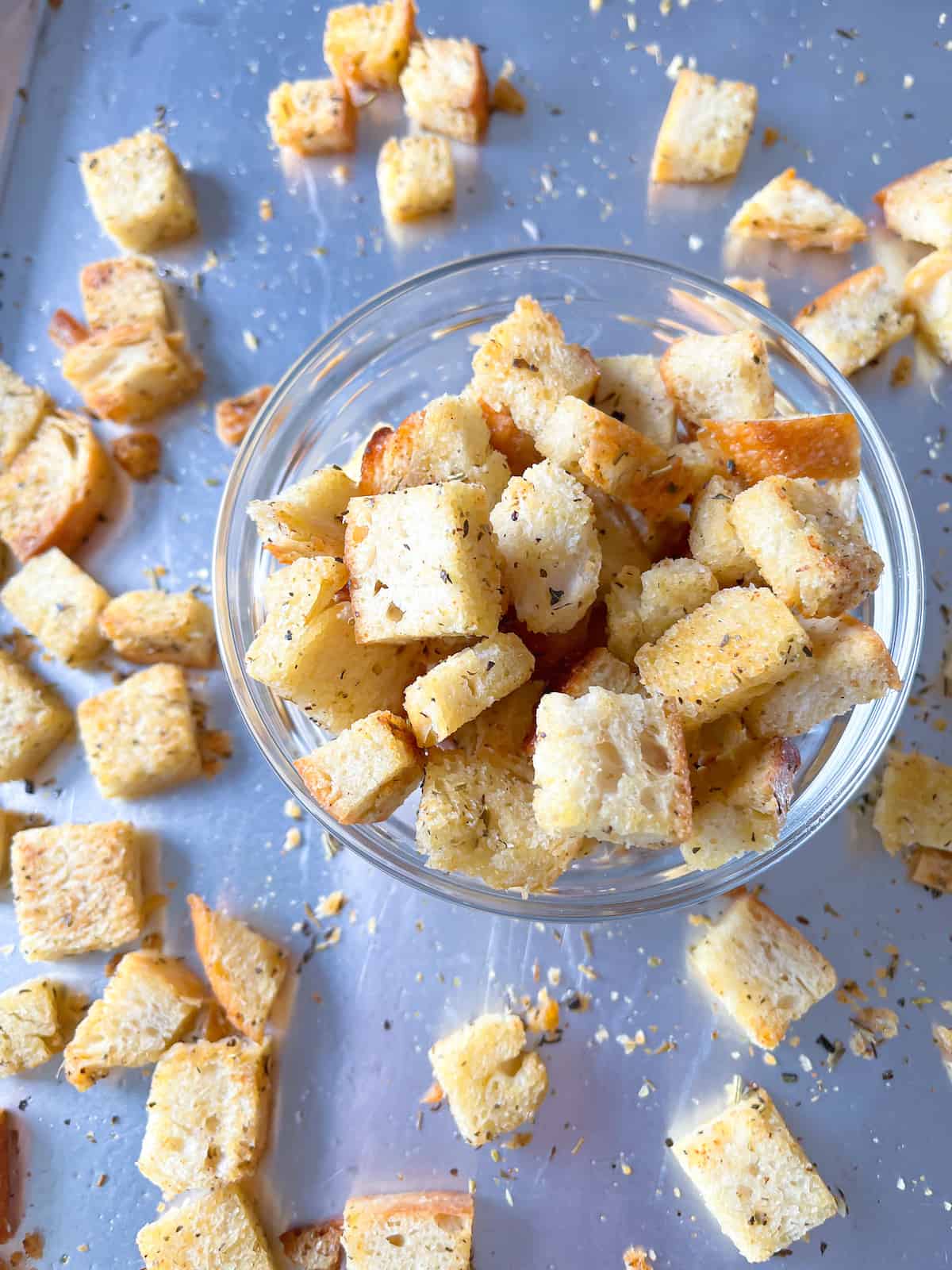 sourdough croutons in a glass bowl with more on a baking sheet in the background