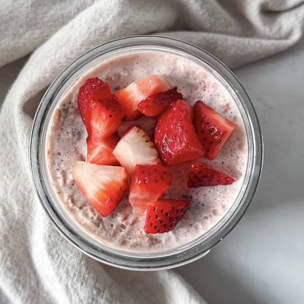 overhead view of strawberries and cream overnight oats in a mason jar.